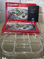 Two new Guzzini acrylic trays with sections visible, displayed with original red and white boxes.