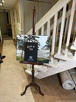 Art stand holding a framed photo with lot number labeled on a chalkboard.