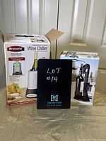 Photo showing Bravetti wine chiller box and corkscrew table set box side by side with lot number display