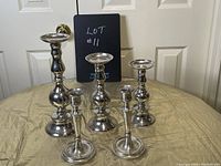 Front view of five metal candle holders arranged on a surface under natural lighting against a white door background.