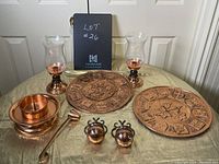 Full view of all copper candle holders, decorative plates, and accessories arranged on a table with beige cloth.