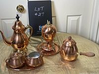 Overview of copper egg cooker set, two teapots, creamer, sugar bowl, and tray