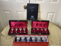 Front view showing all three sets of liqueur goblets in their original cases placed on a table.