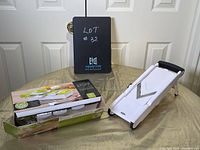 Two white mandolin graters displayed on a table with one still in original packaging beside the other.