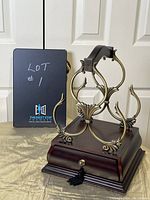 Front view of ornate metal mini wine rack on wooden base with pull-out drawer and tassel knob.