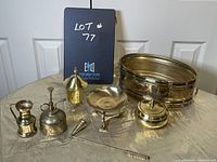 Full view of the assorted brass items grouped together on a table, showing different sizes and shapes including bowls, containers, and smaller decorative pieces