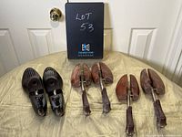 Photo of the six shoe molds and stretchers on a beige tablecloth in front of a white door with a black sign reading 'Lot 53'