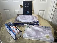 Photo showing three boxed items: a boxed oval stoneware turkey serving platter with embossed turkey design, a boxed glass relish dish with three compartments, and a boxed Proctor Silex electric turkey server in white.