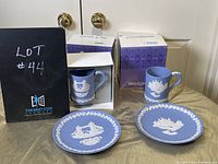 Photo of two boxed Wedgwood Christmas mugs with two matching Christmas plates, all blue jasperware with white relief decoration.