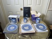 Overall lot showing three Wedgwood Christmas plates and three matching mugs arranged on a table with boxes