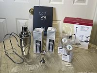 Photo showing full assortment including cocktail shaker, LED wine stoppers, boxed decanting set, stir sticks, jigger, and wine holder stand