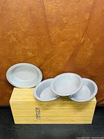 Four round metal cake pans stacked and arranged on a wooden box with the brand name 'Misuda' visible on the box.