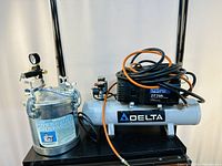 Air compressor and pressure chamber with hoses, showing overall setup and visible labels.