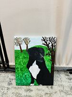 Front view of the colour painting showing a black dog with white chest sitting on green grass with trees
