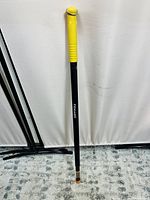 Photo showing full length of Fiskars digging bar with yellow grip and other black metal tool parts against white background.