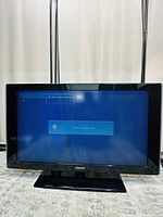 Front view of Samsung 40-inch LCD TV powered on, displaying signal check message, showing black frame and stand.