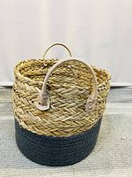 Front view of seagrass basket showing braided seagrass body and leather-like handles, half dyed dark bottom