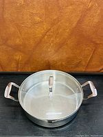 Top view of stainless steel stock pot showing tempered glass lid with handle and two side handles on pot.