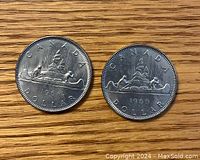 Obverse and reverse sides of two 1968 Canadian one dollar coins, showing designs and dates.