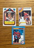 Front of three Ken Dryden hockey cards from 1970s on wood surface