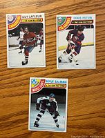 Three front-facing hockey cards on wood surface featuring Guy Lafleur, Denis Potvin, and Borje Salming with team logos and All-Star designations.