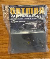 Photo showing sealed Batman Automobilia magazine No.3 with Batman Begins car image on cover and sealed diecast car display case within plastic wrap.