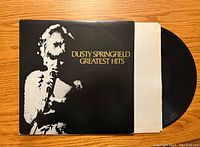 Front cover of "Dusty Springfield Greatest Hits" vinyl record album, black and gold design with image of Dusty Springfield.