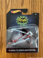 Front view of sealed Hot Wheels Classic TV Series Batcopter toy in original packaging showing batcopter and branding.