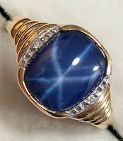 Top-down view of ring face showing blue cabochon star sapphire and accent stones