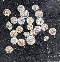 Multiple loose round-cut diamonds of varying sizes placed on black fabric.