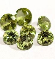 Close-up showing the round faceted cut and light green color of the peridot gemstones.