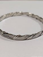 Close up photo showing the twisted rope detail and smooth sections of the silver bangle bracelet.
