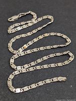 Close-up image of the silver necklace laid out to display chain design and clasp.