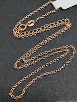 Photo showing entire silver chain necklace laid out on dark background to display full length and structure.