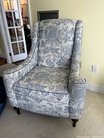 Front view of the armchair showing floral paisley upholstery, seat cushion and legs