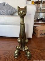 Front view of large brass cat figurine with two smaller cats at the base, showing proportions and design details.