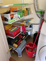 Photo of assorted cleaning and tool items on white wire shelving in a laundry or utility room, includes garbage bags, cleaning cloths, toolbox, and mop bucket.