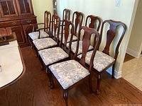 Group view of eight chairs showing side chairs and armchairs in mahogany finish with floral seats