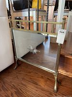 Overall frontal view of the fireplace shield showing brass frame and legs, with mirrored panel and sunburst design detail.