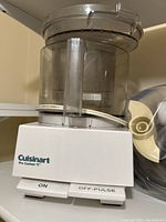 Photo of Cuisinart Pro Custom 11 food processor showing white base with control switch and clear plastic mixing bowl
