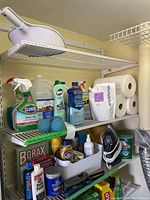 Overview of metal racks with assorted cleaning supplies including Clorox spray, vinegar jug, Vim cleaner, Borax box, and untested iron.