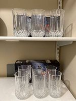 12 clear cut crystal highball glasses displayed on shelves, 8 boxed and 4 unboxed
