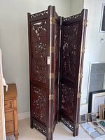Full view of the double stacked wood Korean room divider showing ornate carved details and brass hinges.