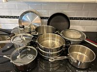 Overview of stainless steel cookware including pots, pans, steamer, cast iron griddle, and strainer