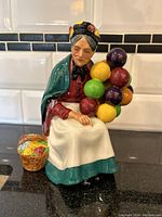 Front view of the Royal Doulton figure showing the elderly woman holding colorful balloons and a basket beside her.