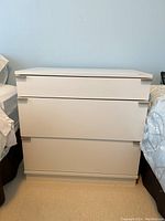 Front view of small white dresser showing three drawers with integrated handles.