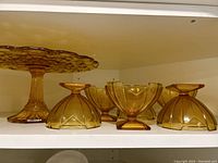 Full view of the vintage amber glass cake stand and six dessert dishes on a shelf