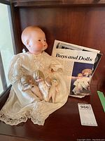 Composite photo showing one large doll with porcelain head and three small porcelain dolls alongside a newspaper clipping.