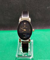 Close-up front view of Bella & Rose ladies dress watch showing black oval dial with gold hands and logo, and enamel segments on band.