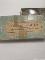 Original box with label reading '6 Piece Glass Candle Saucers, Bobeches, Will & Baumberg Candle Co., Syracuse, N.Y., Code 700' with some tape residue on box.